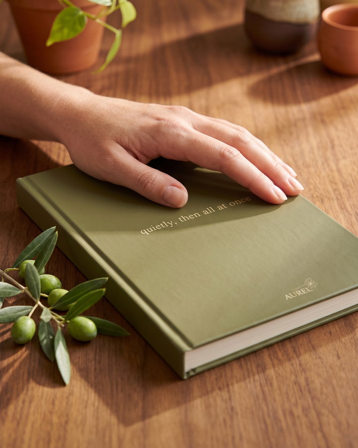 A hand resting on an AUREL olive journal